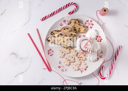 Bouteille de lait avec un stollen de Noël traditionnel, petits biscuits et canne à sucre sur fond blanc. Pain de Noël allemand Banque D'Images