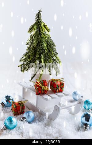 Paysage enneigé avec arbre de Noël et petits cadeaux en traîneau. Décoration de Noël Banque D'Images