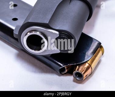 Un pistolet semi-automatique noir de calibre 1911 45 avec un magasin chargé sous lui sur un fond blanc Banque D'Images