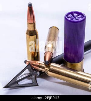 Trois balles de fusil de chasse de calibre différent avec une tête large flèche et une carabine violette sur fond blanc Banque D'Images