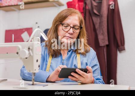 Femme d'affaires chilienne âgée avec un téléphone intelligent. Professionnel latin mature entrepreneur needlewoman Banque D'Images