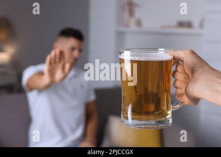 Homme refusant de boire de la bière dans la cuisine, gros plan. Traitement de la dépendance à l'alcool Banque D'Images