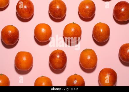 Beaucoup d'oranges siciliennes mûres sur fond rose, couché à plat Banque D'Images