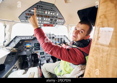 Un homme vêque de façon décontractée est assis dans le cockpit de l'avion et regarde derrière lui Banque D'Images