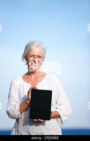 Trouver de nouveaux exercices en ligne. Portrait d'une femme mûre tenant une tablette numérique debout à l'extérieur. Banque D'Images