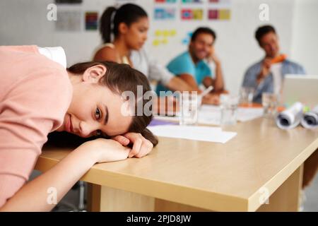 Cette réunion est prévue pour des âges. Gros plan d'une jeune stagiaire qui se repose la tête sur une table de réunion pendant une réunion. Banque D'Images