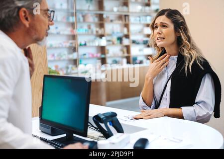 Patient avec un rhume parlant à un pharmacien au comptoir. Fournisseur de soins de santé aidant une femme dans une pharmacie. Banque D'Images