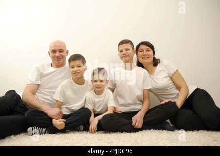 Famille sympathique. Mari avec trois fils est couché près de la mère enceinte , isolée sur fond blanc. Parents heureux. Mère enceinte et père avec enfants. Concept de personnes et de famille. Banque D'Images