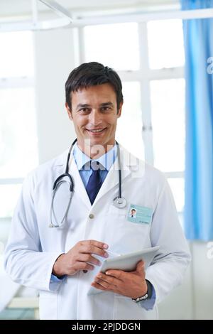 Toutes vos antécédents médicaux d'une seule main. Portrait d'un beau jeune médecin utilisant un comprimé. Banque D'Images