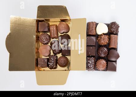 boîte cadeau ouverte dorée plusieurs bonbons au chocolat au lait foncé de grande variété Banque D'Images