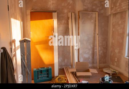 Portes et cadres de porte inclinés sur le mur. Échelle et outils se trouvant autour de la pièce. Projet de rénovation de la maison. Auckland. Banque D'Images