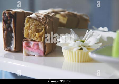 Encore la vie avec les barres de savon à la main pressées à froid enveloppées dans du papier artisanal sur la surface blanche. Concept de spa et de relaxation du corps à la maison Banque D'Images