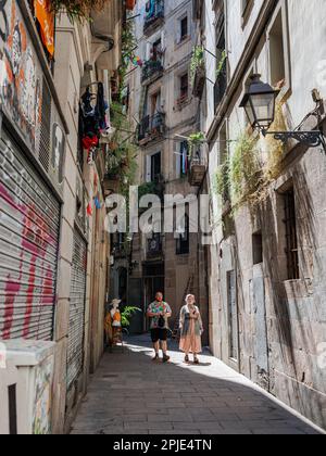 Couple marchant dans une étroite rue de Barcelone avec un ancien lampadaire dans le quartier gothique de Barcelone, Espagne. Banque D'Images