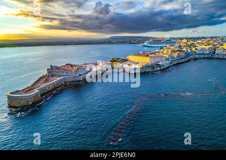 Vue aérienne du château de Maniace, de l'île d'Ortigia et de la ville de Syracuse baignée dans la lumière chaude du coucher du soleil. Syracuse, Sicile, Italie Banque D'Images