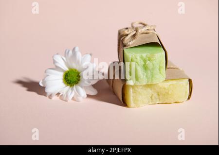 Encore la vie avec des barres de savon pressé à froid bio fait à la main avec des ingrédients naturels et une fleur de camomille sur fond rose Banque D'Images