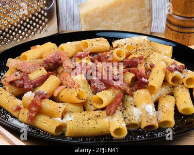 Le rigatoni Pasta alla grincia est un plat typique de la région du Latium. Juste joue de porc, pâtes rigatoni, fromage pecorino Romano, poivre fraîchement râpé. Banque D'Images