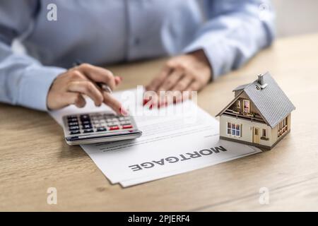 Détail des mains des femmes en utilisant la calculatrice pour connaître le taux d'intérêt sur une hypothèque de maison. Banque D'Images