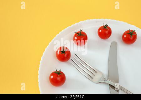 Chey Tomatoes horloge sur l'assiette avec des couverts. Alimentation Banque D'Images