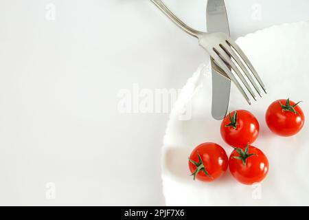 Faire des tomates sur une assiette avec des couverts. Concept alimentaire. Banque D'Images