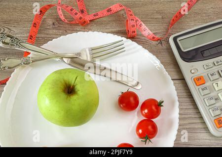 Sur une assiette à couverts, une calculatrice pour compter les calories et un mètre à ruban. Banque D'Images