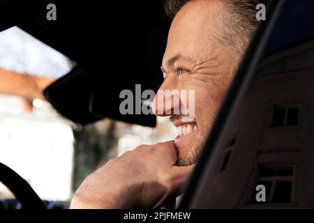 Heureux souriant homme d'affaires attrayant dans un tissu décontracté conduite d'une voiture dans la ville, essai de conduite Banque D'Images