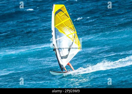 Sports aquatiques: Planches à voile sur une vague avec une voile orange sur l'océan Atlantique Banque D'Images