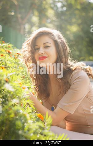 portrait de la femme souriante pose sur fond de lit de fleurs Banque D'Images