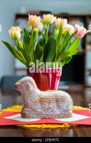 Gros plan d'un gâteau allemand « Osterlamm » / agneau Pascal devant un bouquet de tulipes joliment décoré dans une maison Banque D'Images