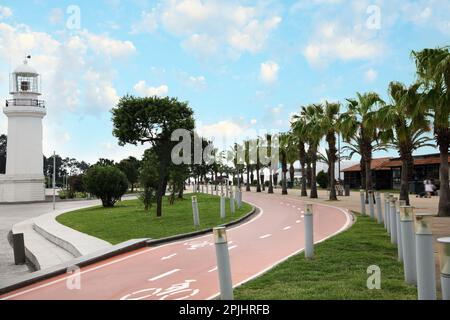 Rue de la station balnéaire avec phare, palmiers et piste cyclable à deux voies Banque D'Images