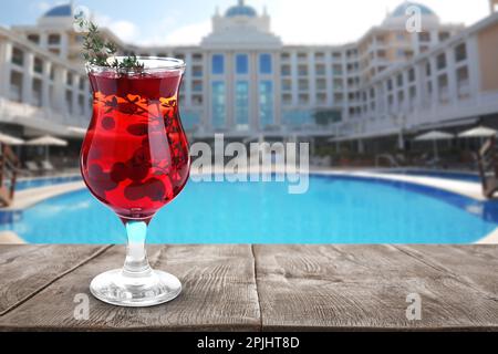 Délicieux cocktail rafraîchissant sur une table en bois près de la piscine extérieure de l'hôtel, espace pour le texte Banque D'Images