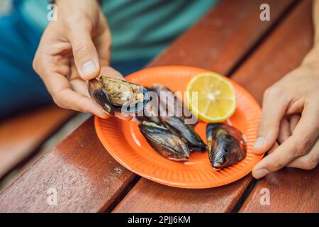 Tas de moules en coquilles farcies de riz. L'homme va manger de la nourriture traditionnelle turque midye. Istanbul, Turquie Banque D'Images