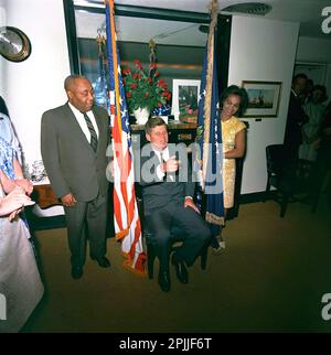 KN-C28776 29 mai 1963 le Président John F. Kennedy assiste à un anniversaire surprise tenu en son honneur par des membres du personnel de la Maison Blanche. Le valet du président Kennedy, George E. Thomas, est à gauche ; une femme non identifiée se trouve à droite. Visible sur la porte tout à droite : Ron Pontius, agent du service secret de la Maison Blanche, Evelyn Lincoln, secrétaire personnel du président Kennedy. Navy Mess Hall, Maison Blanche, Washington, D.C. Veuillez indiquer « Cecil Stoughton ». Photos de la Maison Blanche. John F. Kennedy Library and Museum, Boston Banque D'Images