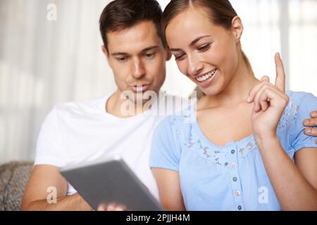 À mon tour de jouer. Un petit cliché d'un jeune couple heureux jouant à des jeux sur leur tablette. Banque D'Images