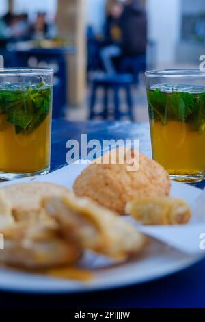 Thé à la menthe et délicieuses pâtisseries traditionnelles sur une table bleue à Rabat Maroc Banque D'Images