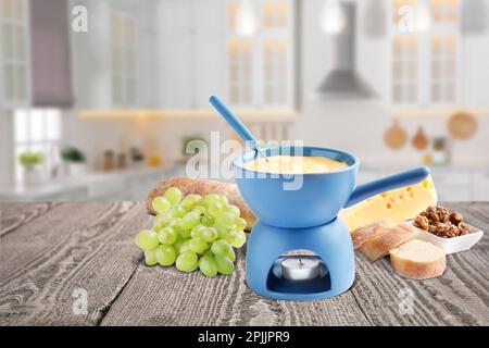 Composition avec une casserole de fondue au fromage sur une table en bois dans la cuisine Banque D'Images