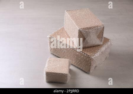 Boîtes en carton recouvertes d'un film à bulles sur une table gris clair Banque D'Images