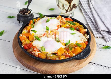 Shakshouka dans une poêle. Œufs frits avec légumes, tomate, poivre, citrouille et oignon Banque D'Images