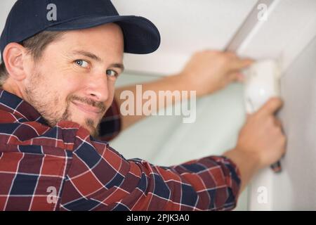 l'entrepreneur installe le détecteur dans le coin de la pièce Banque D'Images