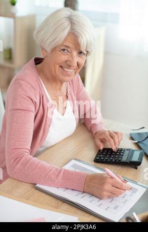 une femme âgée assise à la table à la maison gère son budget Banque D'Images