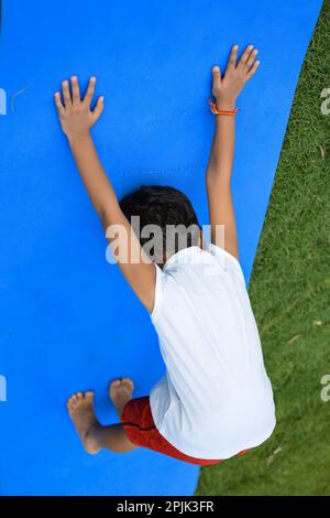 Asiatique chic enfant faisant le yoga pose dans le parc de la société en plein air, pose de yoga pour enfants. Le petit garçon faisant de l'exercice de yoga Banque D'Images