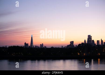 Des nuages rayés de radiatus altostratus roses, violets et orange couvrent le ciel au coucher du soleil sur les gratte-ciel de Londres. Banque D'Images