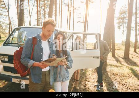 Recherche d'une position à l'aide de la carte. Groupe de jeunes voyagent ensemble dans la forêt pendant la journée Banque D'Images