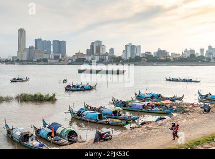 Phnom Penh,Cambodge-24 décembre 2022:sur le côté est beaucoup moins développé de la rivière, les gens vivent et travaillent dans l'artisanat de style canoë, partiellement couvert Banque D'Images