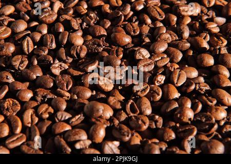 Fond de grains de café. Gros plan sur la texture des grains de café. Le café torréfié brun foncé tourne. Abondance. Concept pour la publicité des produits du café. S Banque D'Images
