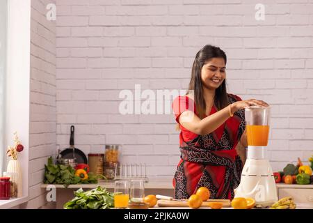 Femme faisant le jus d'orange dans la cuisine Banque D'Images