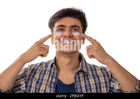 Portrait d'un homme joyeux appliquant de la crème pour le visage sur fond blanc Banque D'Images