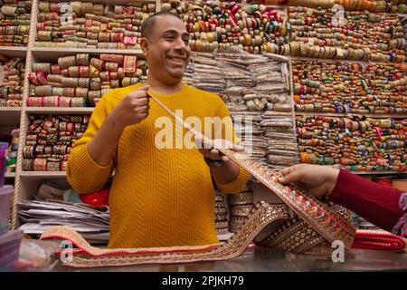 Vendeur de tissu masculin montrant la frontière et la dentelle à un acheteur féminin Banque D'Images