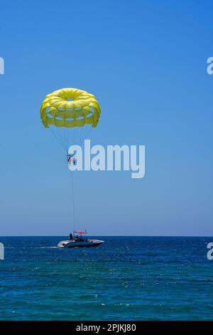 Parachute ascensionnel sur un parachute jaune contre le ciel bleu. Aventures extrêmes sur la plage. Vacances de fond, photo pour cartes postales, guide touristique et de voyage Banque D'Images