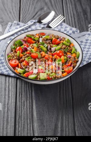 Salade de lentilles d'été avec oignons, carottes, concombres, poivrons et tomates dans une assiette sur une table en bois. Verticale Banque D'Images