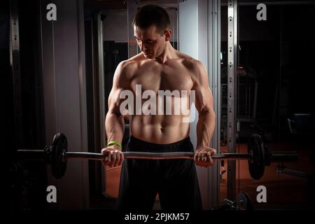 Homme fort - carrossier avec haltères en une salle de sport, l'entraînement avec un barbell Banque D'Images